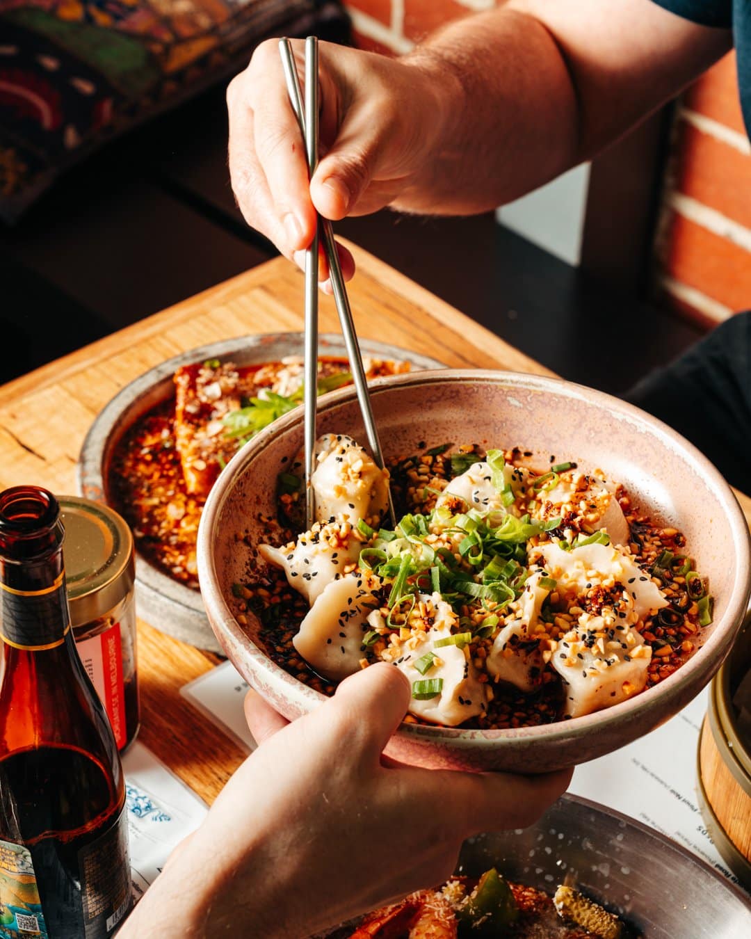 Food photography of customer picking up dumplings with chopsticks from a restaurant marketing campaign.