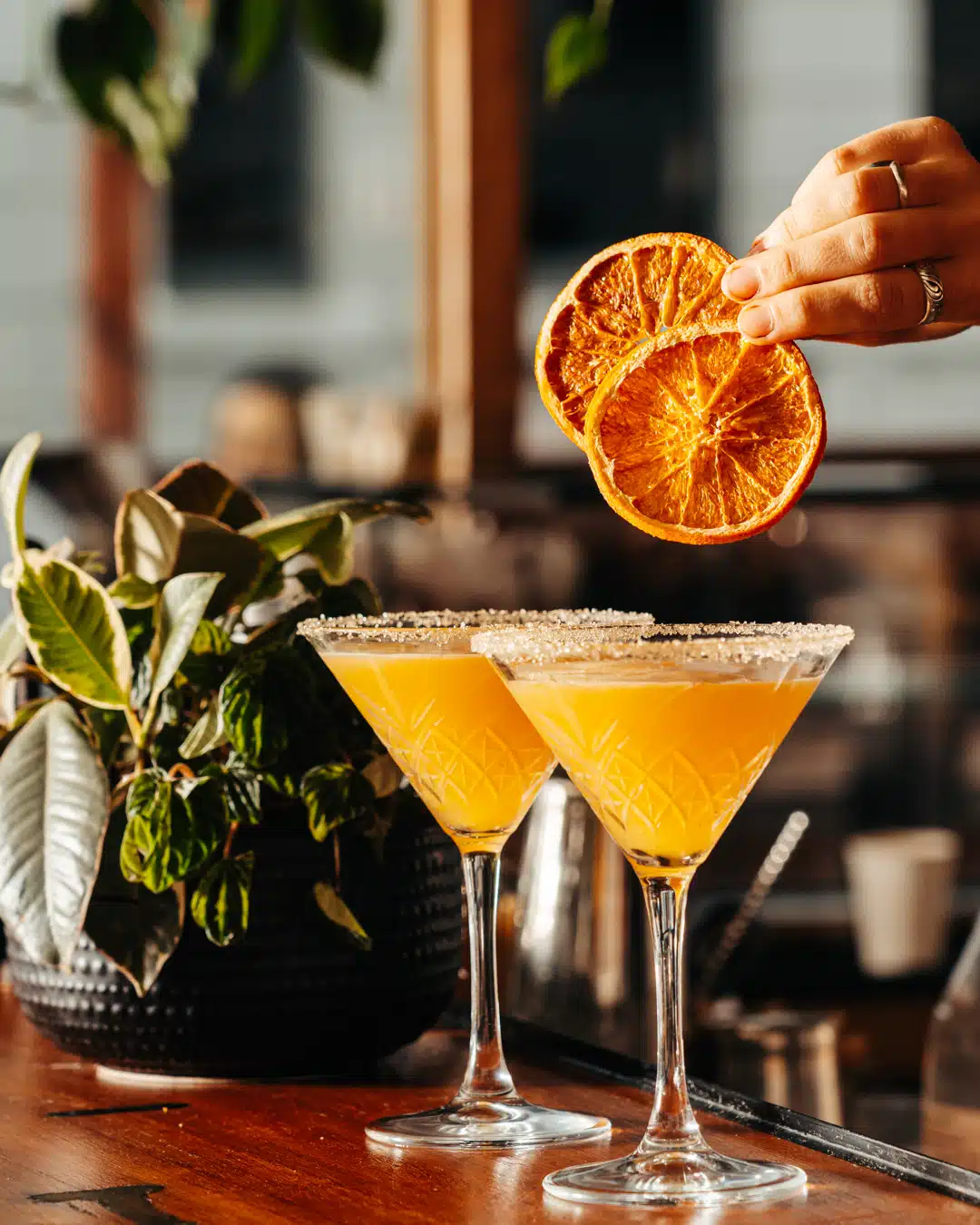 Drink photography of bartender garnishing two cocktails from a bar marketing campaign.