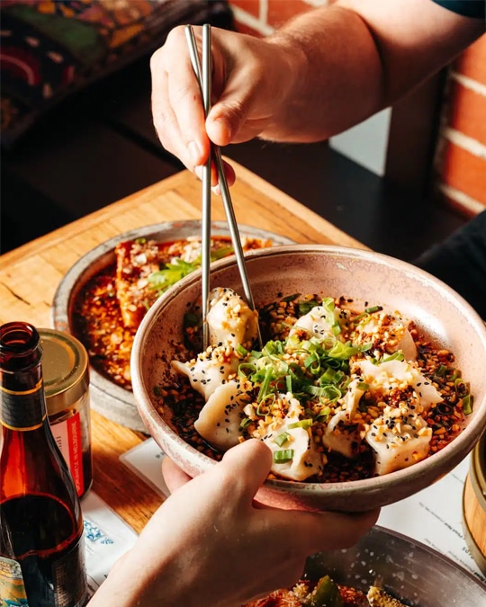 Food photography of customer picking up dumplings with chopsticks from a restaurant marketing campaign.