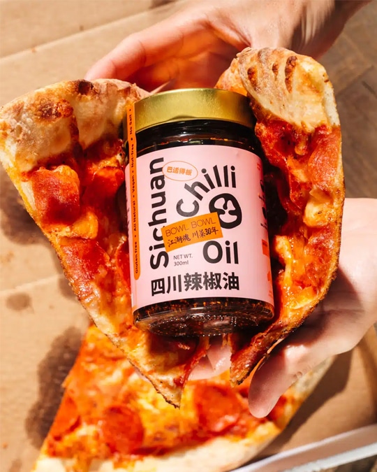 Food photography of jar of chilli oil and pizza from a hospitality marketing campaign.